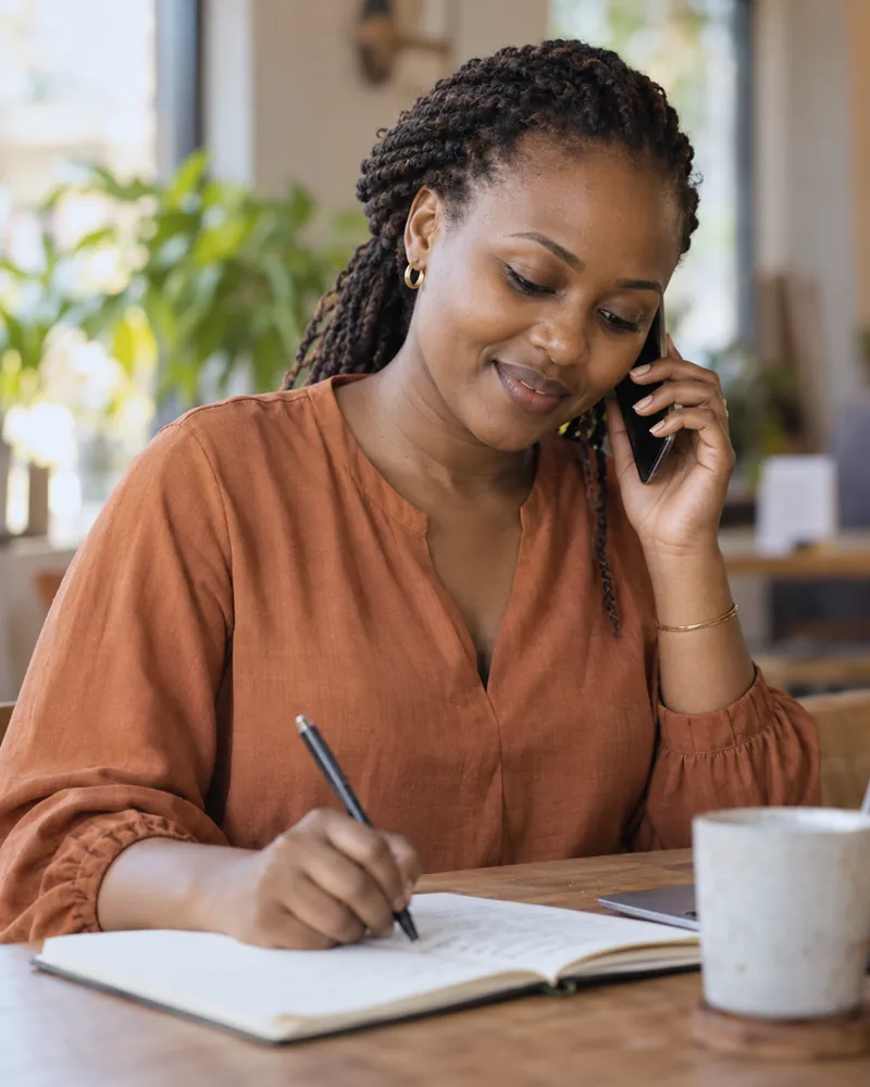 A client on the phone with her broker, taking notes